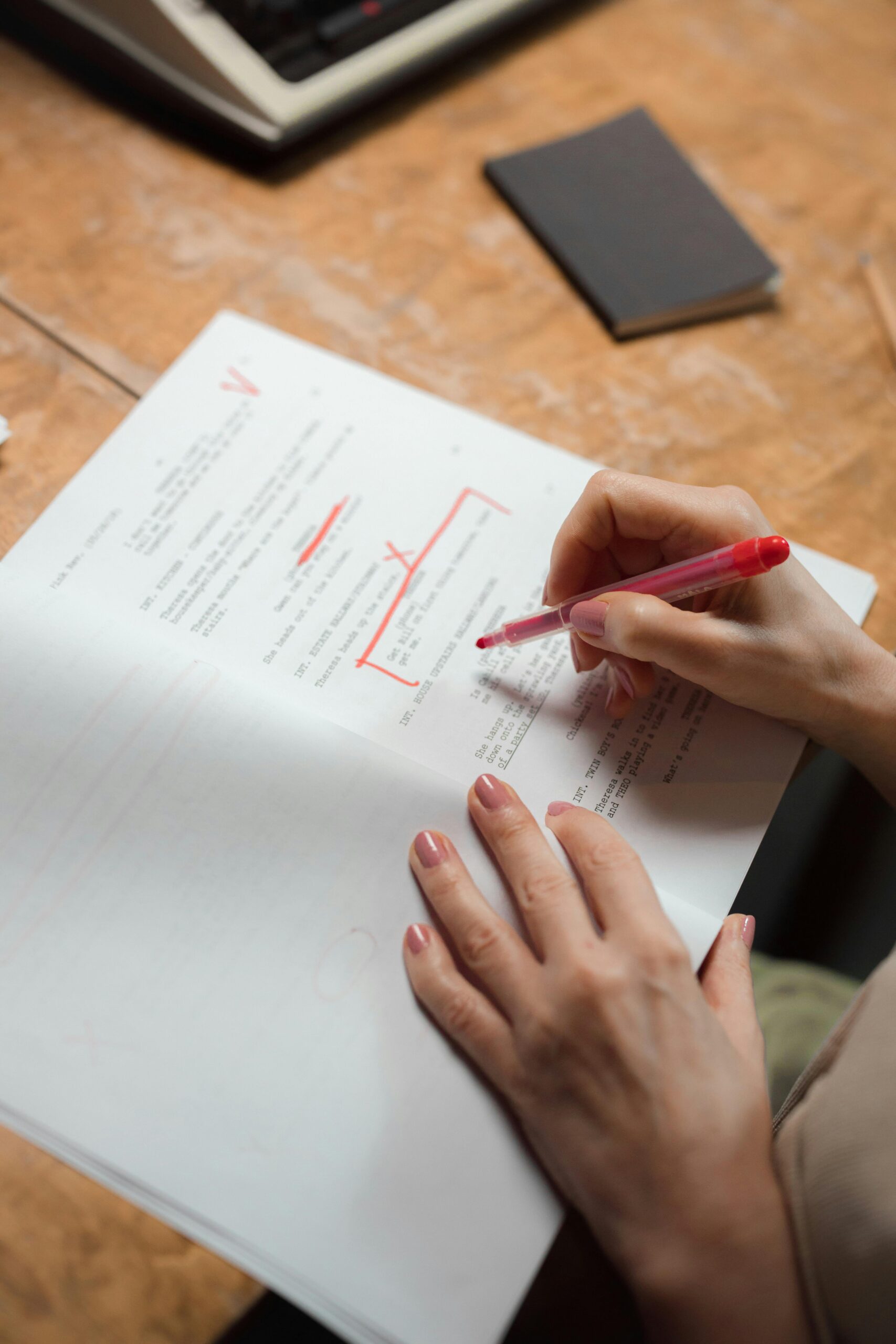A close-up view of a hand using a red pen to edit a manuscript. Ideal for editorial and writing themes.